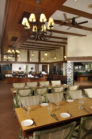 A spacious dining area with multiple tables and chairs, a central bar, and a ceiling fan.