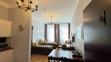 Una habitación de hotel con comedor, una araña, un reloj y una cama con almohadas.