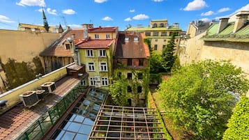 Un edificio de varios pisos con terraza en la azotea, invernadero de cristal y vistas de edificios circundantes.