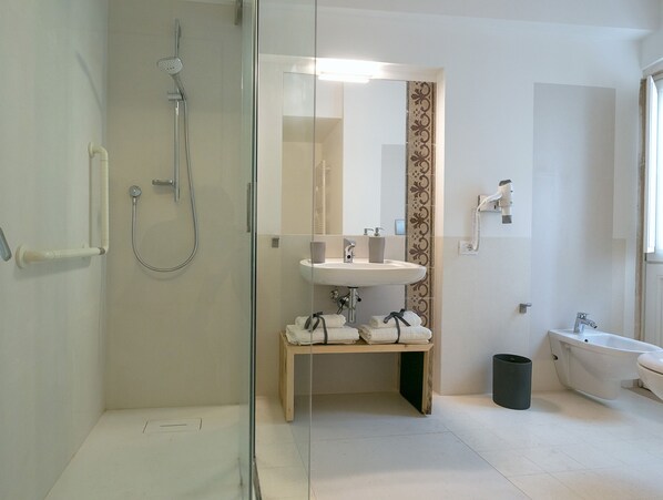 Un baño moderno con ducha de vidrio, lavamanos con espejo, inodoro y bañera.