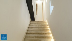 A staircase with white walls and a wooden handrail. - Dione Apartments Ortigia (Syracuse)