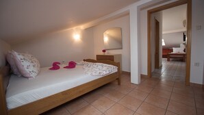 Ein Schlafzimmer mit einem Einzelbett, einem Nachttisch, einem Spiegel und einer Tür zu einem anderen Raum.