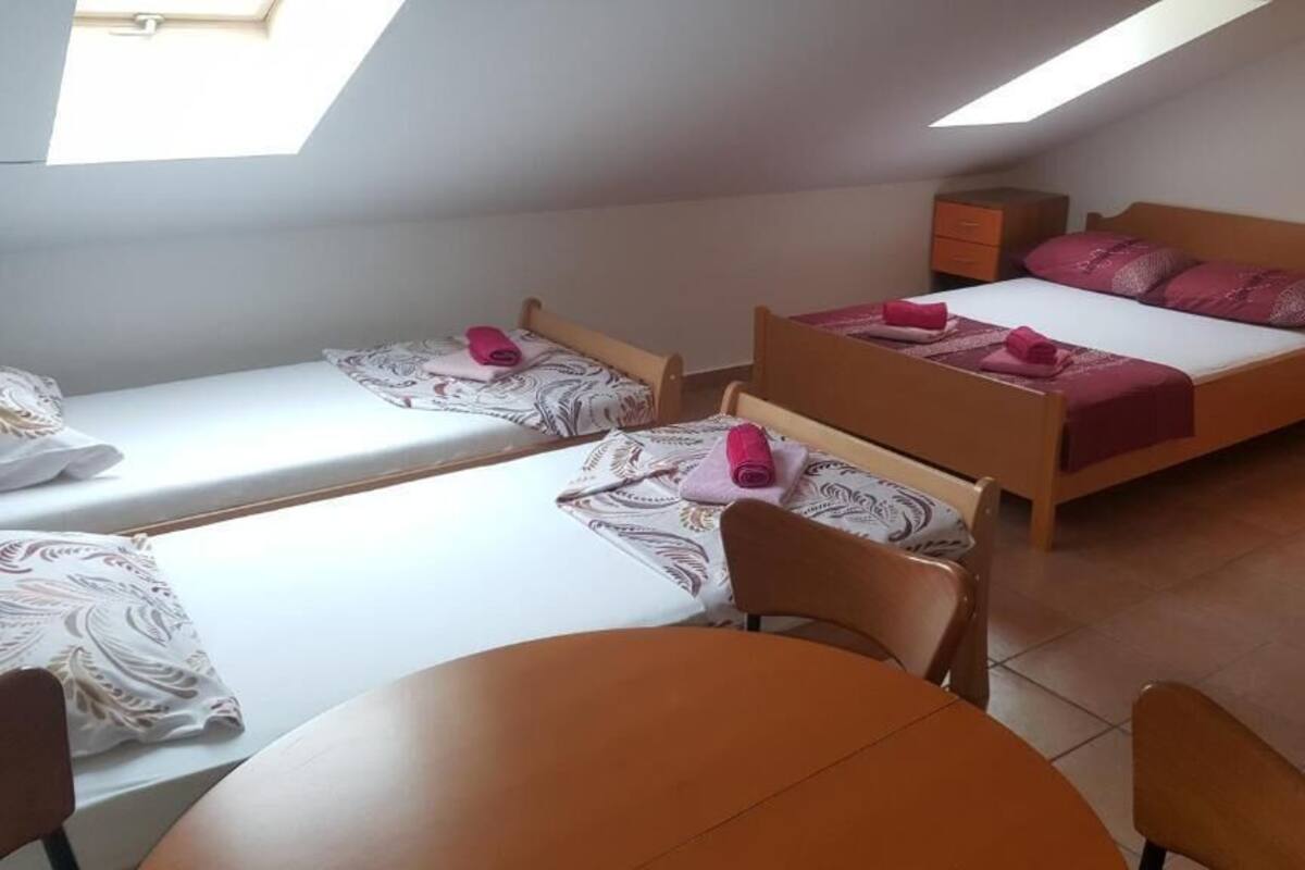 A dormitory room with two single beds, a small table, and a chair.