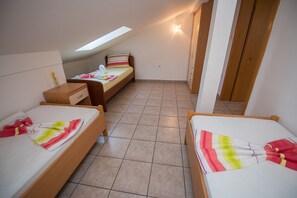 A bedroom with two beds, a desk, and a wardrobe.