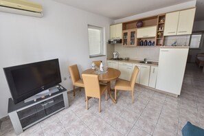 A compact kitchen with a dining area, a TV, and a built-in entertainment unit.