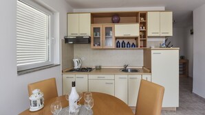 Eine moderne Küche mit weißen Schränken, einem Esstisch mit Stühlen und einem Fenster mit Jalousien.