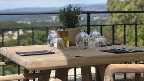 A wooden table set outdoors with a view of the landscape. - Mougins Luxury Retreats (Mougins)