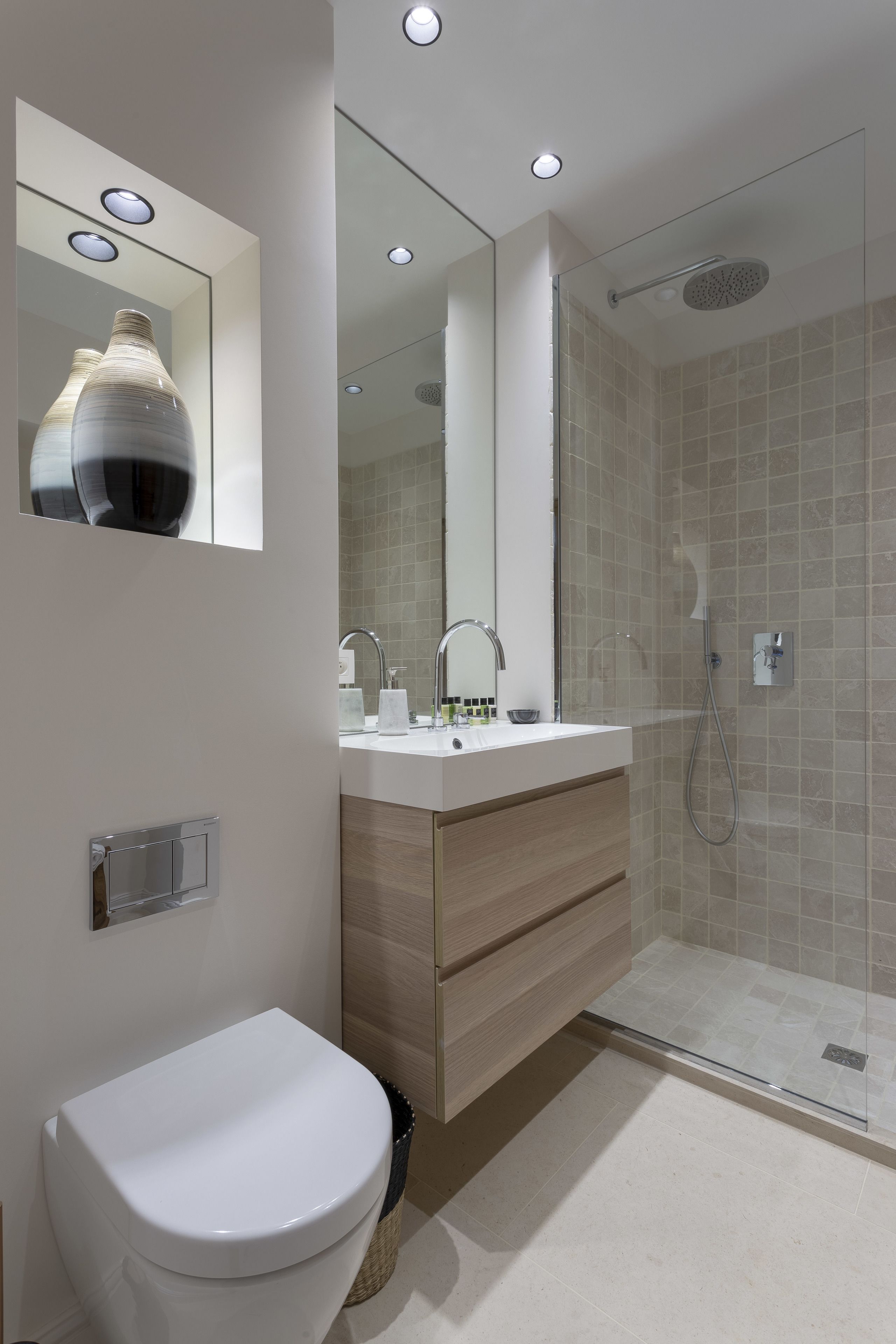 A modern bathroom with a white sink, mirror, and toilet.