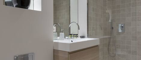 A modern bathroom with a white sink, mirror, and toilet.