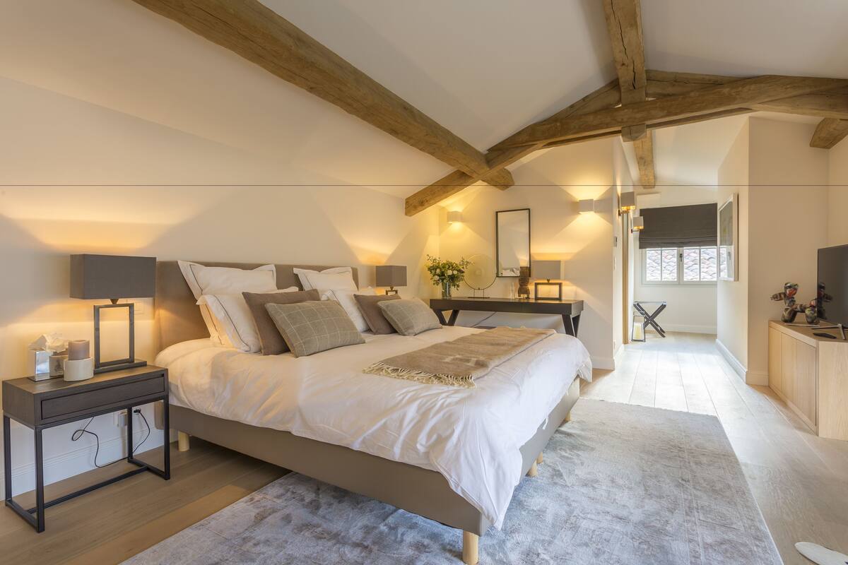 Quarto com uma cama grande, mesas de cabeceira e teto de madeira.