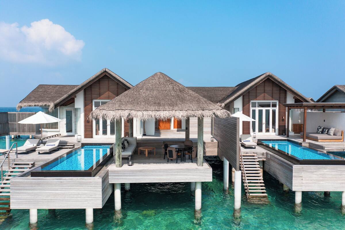 Wasserbungalows mit Infinity-Pools, Holzterrassengängen und strohgedeckten Strukturen.