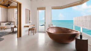Ein geräumiges Badezimmer mit einer großen Kupferbadewanne, einem Holzwaschtisch und Blick auf den Ozean.