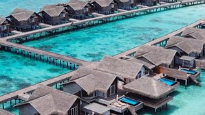 Wasserbungalows mit Privatpools, verbunden durch Wege über klares, türkisblaues Wasser.