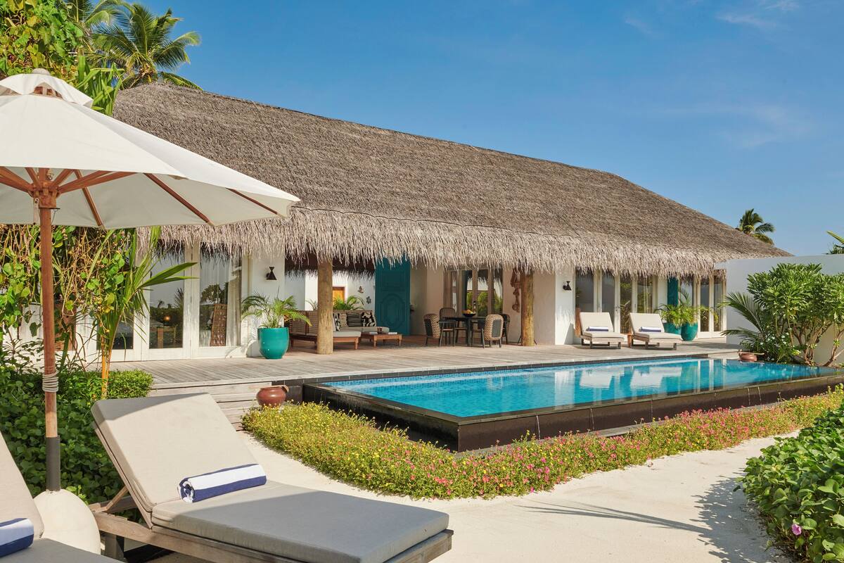 Ein Resort mit Pool, Liegestühlen und einem Gebäude mit einem Reetdach.