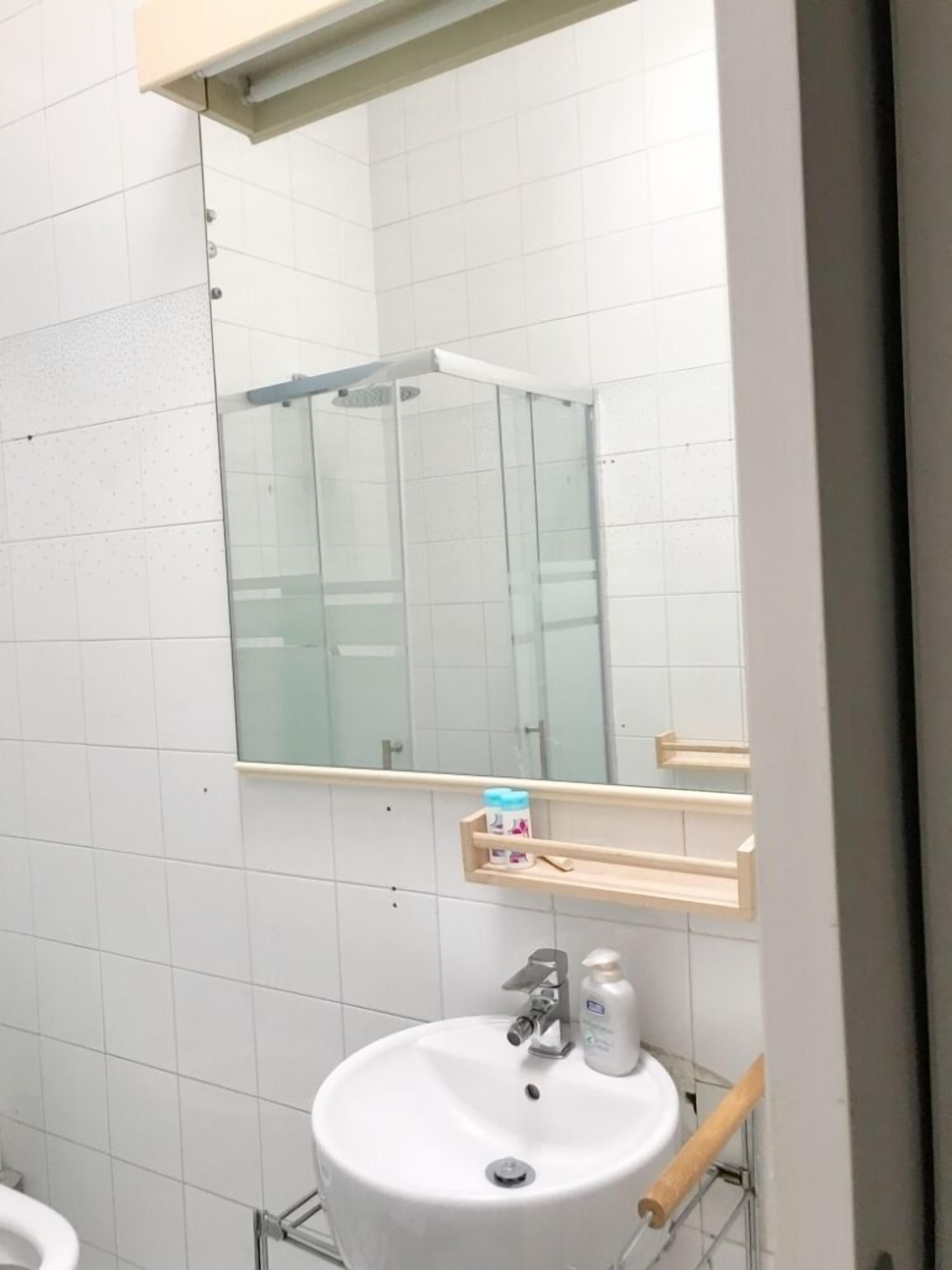A bathroom with a white sink, a mirror, and a shower enclosure.