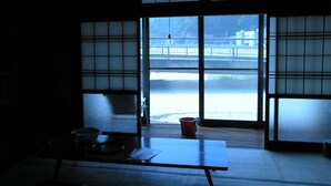 Una habitación japonesa tradicional con suelo de tatami, una mesa baja y puertas correderas que dan a una vista de un paisaje nevado.
