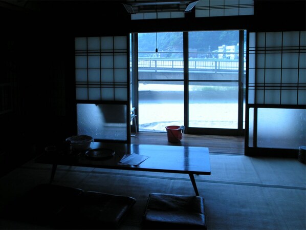 Una habitación japonesa tradicional con suelo de tatami, una mesa baja y puertas correderas que dan a una vista de un paisaje nevado.