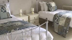 A bedroom with two beds, white bedding, and a patterned throw. - The White House Wells 2 Park View (Wells)