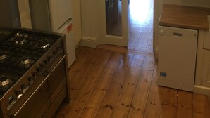 A kitchen with a stainless steel stove, a white refrigerator, wooden flooring, and a door leading to a dining area. - The White House Wells 2 Park View (Wells)