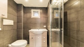 A modern bathroom with a toilet, a sink, and a shower area. - Luxury House (Naples)