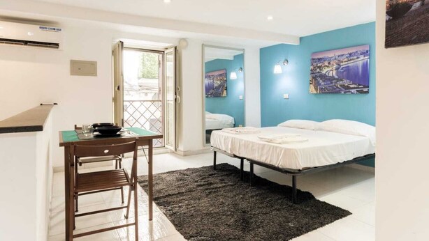A bedroom with a bed, a desk with a chair, a window, and a door leading to a balcony. - Luxury House (Naples)