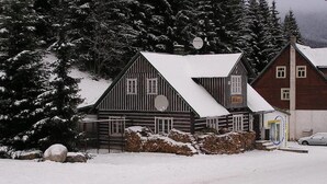 Een houten hut met een met sneeuw bedekte dak, omringd door sneeuw bedekte bomen.