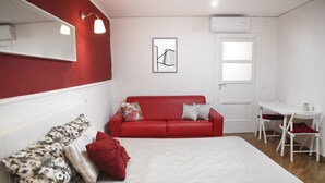 A room with a bed, a red sofa, a small white table, and a chair. - Colorful Sea View Apartments (Naples)