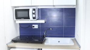 A compact kitchen with white cabinets, a microwave, a sink, and a small refrigerator. - Colorful Sea View Apartments (Naples)