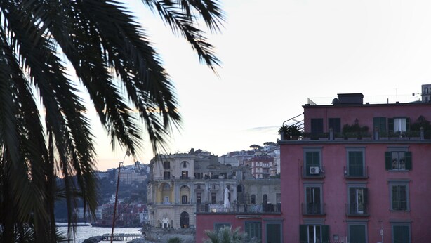 A coastal cityscape with historic buildings, including a pink building with green shutters and a yellow building with arched windows. - Colorful Sea View Apartments (Naples)