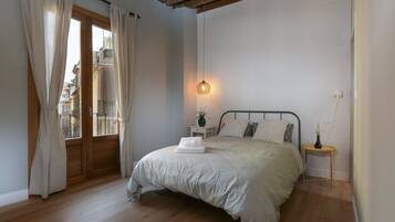 A bedroom with a bed, a bedside table, a lamp, and a window with curtains.