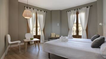 A modern hotel room with a large bed, a chair, a small table, and a hanging light fixture.