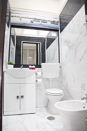 A modern bathroom with a white sink, toilet, and bathtub. - Sermoneta Apartments (Naples)