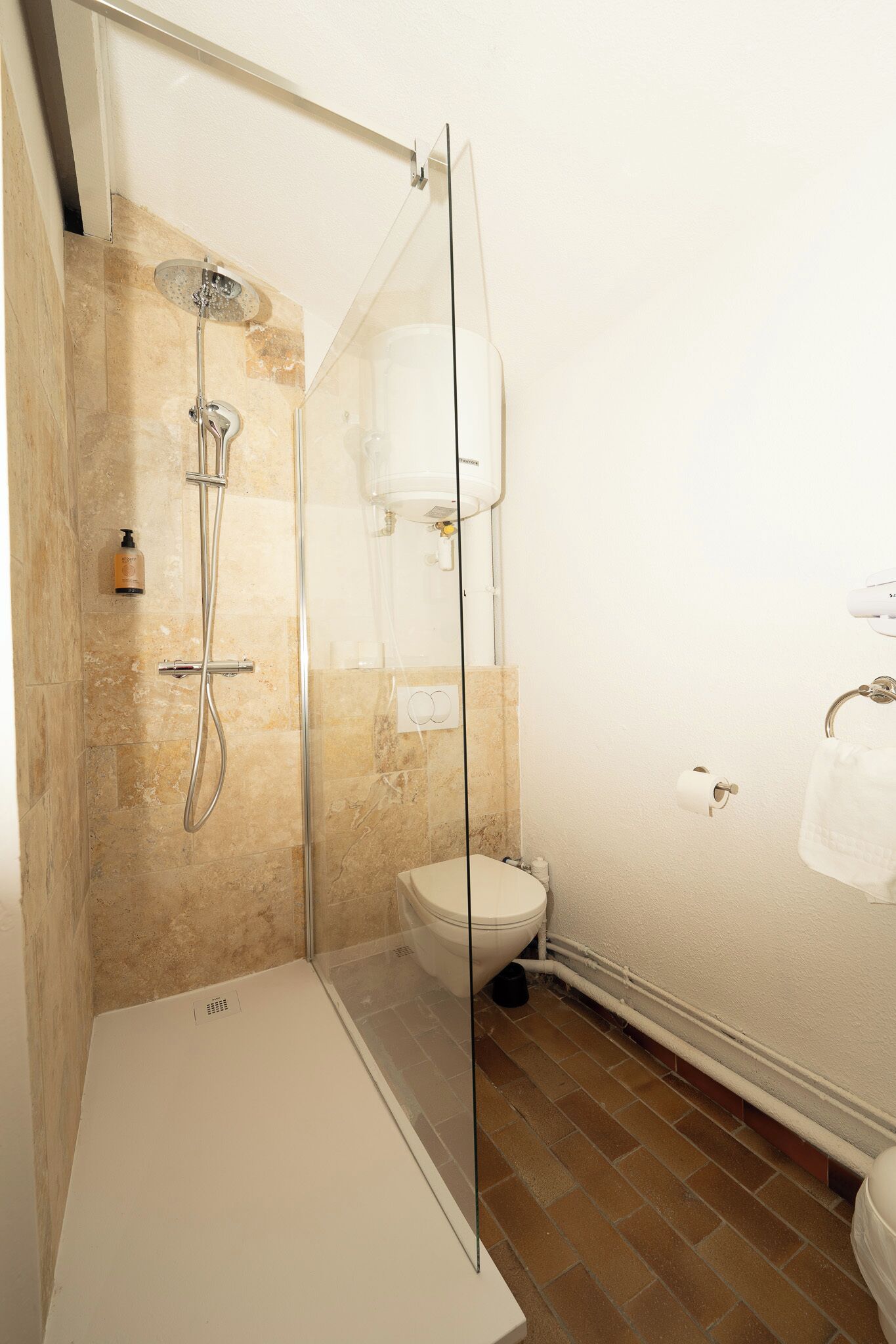 A bathroom with a glass-enclosed shower, a toilet, and a sink.