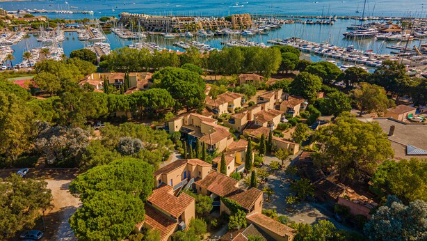A coastal village with traditional architecture, a marina with numerous boats, and lush greenery. - Marina Hotel Club (Cogolin)