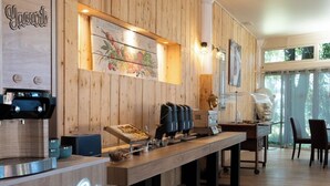 A restaurant with wooden walls, a neon sign, a pizza station, and a window view. - Marina Hotel Club (Cogolin)