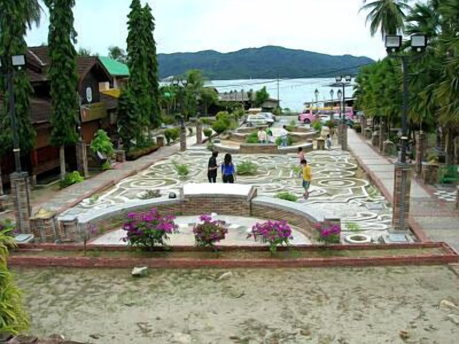 Un jardín ajardinado con senderos, una fuente central y abundante vegetación.