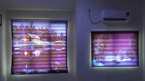 Twee grote ramen met wintertaferelen, een wandairconditioner en een betegelde vloer.