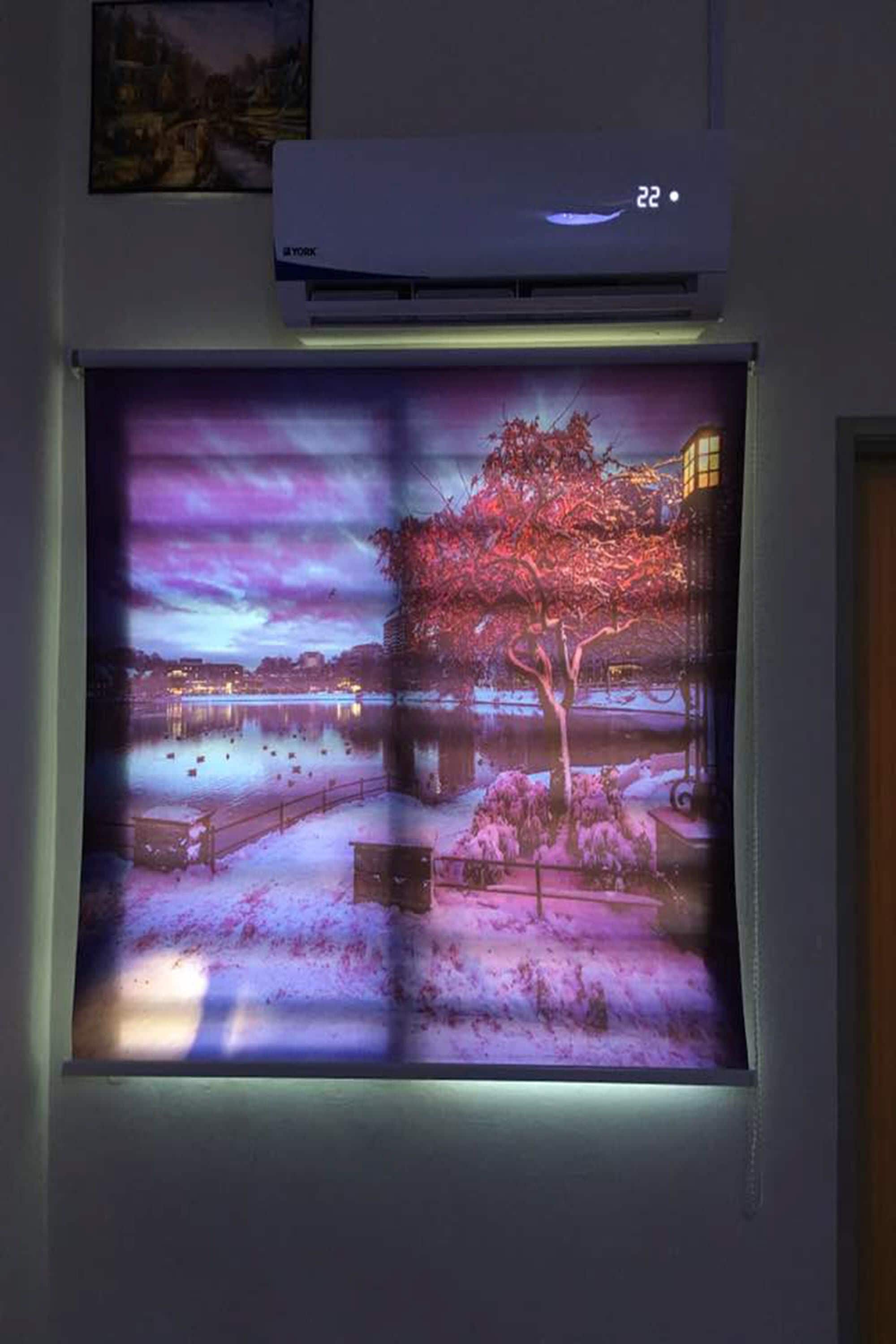 A projection of a scenic winter landscape with a tree, snow, and a building in the background.