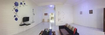 Uma sala de estar espaçosa com televisão de tela plana, sofá e mesa de centro.