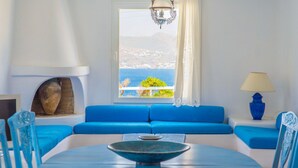 Et værelse med en blå sofa, et bord med en skål, en lampe og havudsigt.
