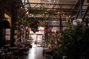 An indoor market with wooden shelves, tables, and hanging plants.