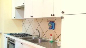 Una cocina con armarios blancos, estufa a gas, pileta y salpicadero de azulejos.