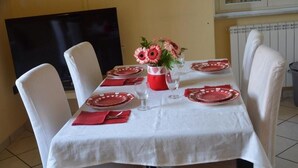 Una mesa de comedor con platos blancos y rojos, un jarrón con flores y un guardanapo rojo.