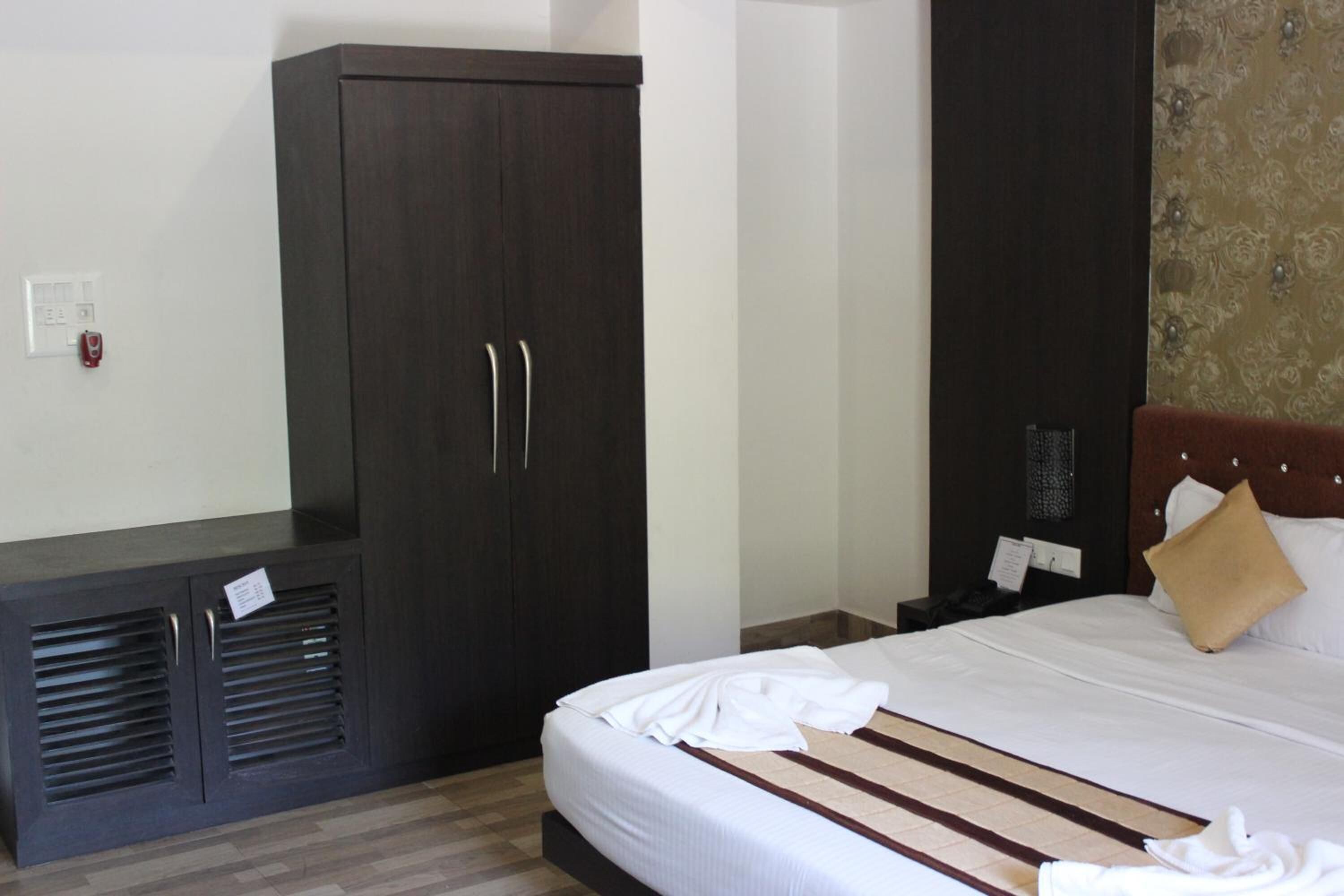 Una habitación de hotel con un armario grande, una cama con sábanas blancas y un cabecero decorativo.