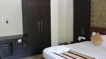 Una habitación de hotel con un armario grande, una cama con sábanas blancas y un cabecero decorativo.