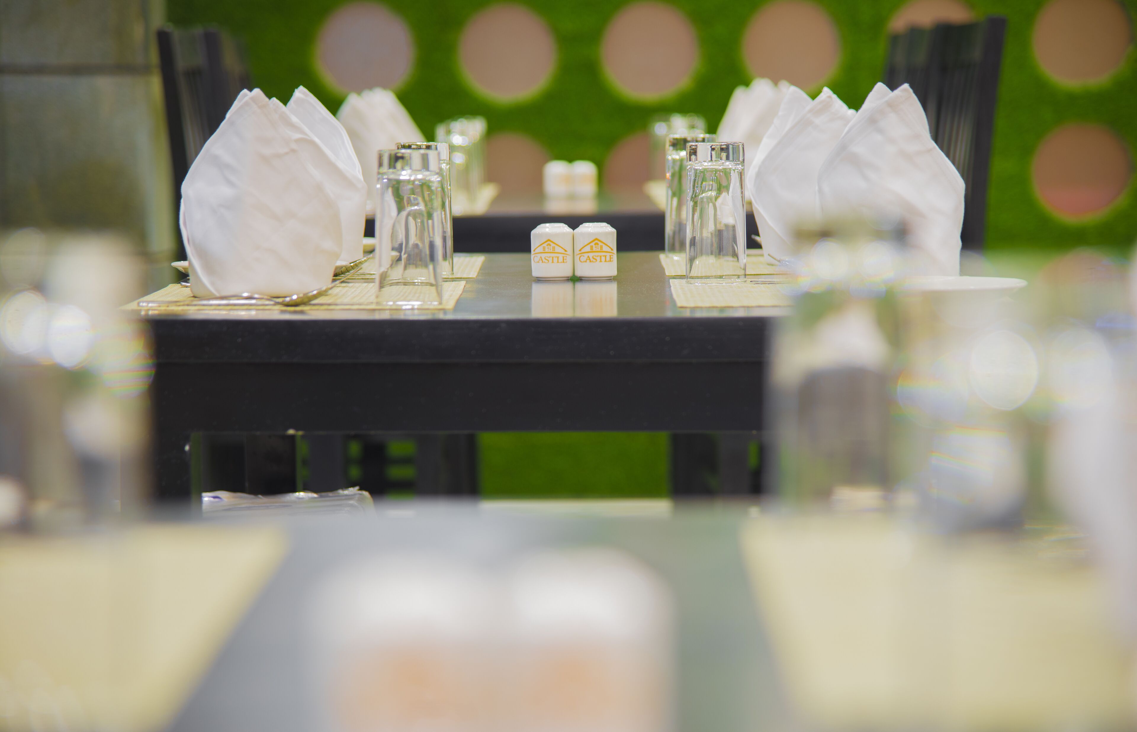 Een eettafel, gedekt met witte servetten, glazen en een fles Castle bier.