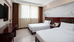 A hotel room with two beds, a desk, a TV, and a window with curtains. - Kaiserdom Changsha South Station (Changsha)