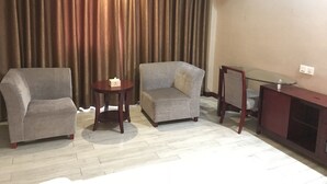A living room with a grey sofa, a smaller armchair, a round wooden table, and a glass-top coffee table. - Kaiserdom Changsha South Station (Changsha)