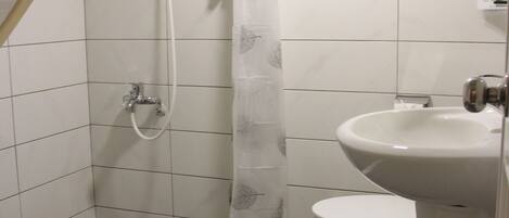 Une salle de bain avec une douche, des toilettes et un porte-serviettes.