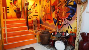 Ein lebendiger Raum mit einer Treppe, einem Schlagzeugset und einem großen abstrakten Wandgemälde.
